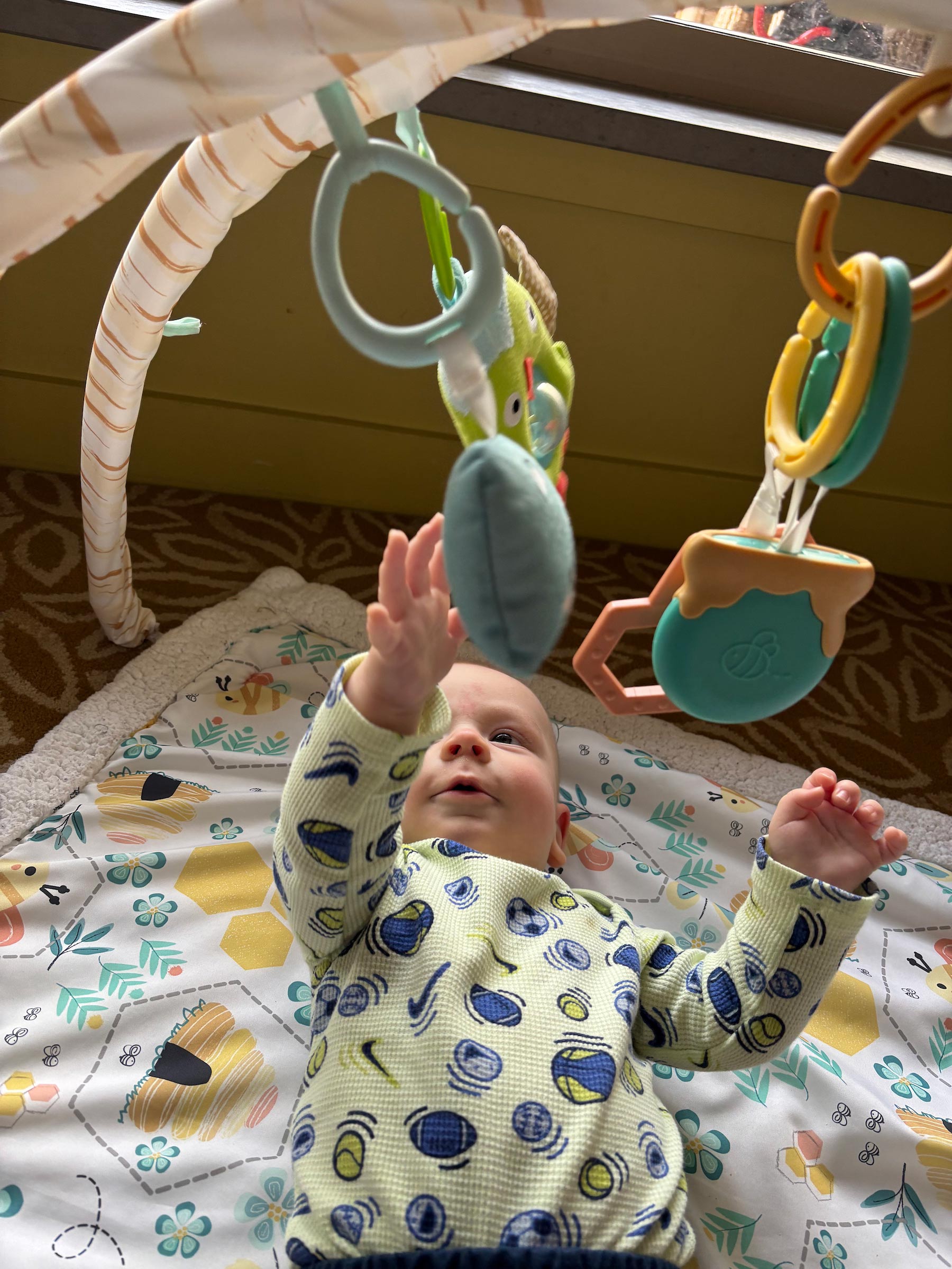 Baby reaches up at a mobile toy.