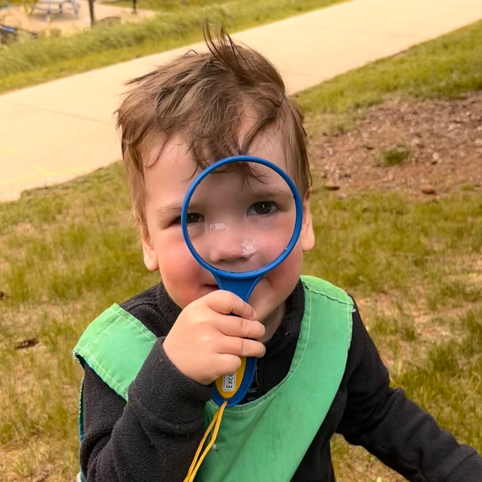 Child's face looking through a magnifying glass.